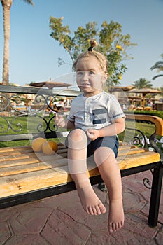 Happy kid or little boy barefoot with orange fruit