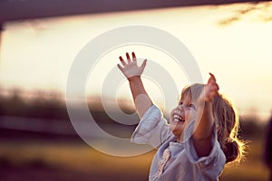 Happy kid looking at the sky . fun on countryside, sunset golden hour. Freedom nature concept