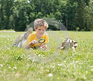 Happy kid with magnifying glass outdoors.