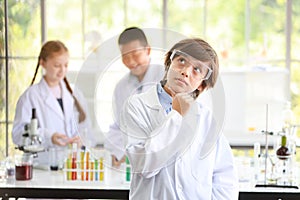 Happy kid making science experiments and confident. he pose thinking of something with another kids blurred background education