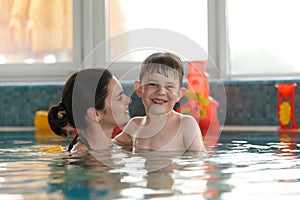 Happy kid and mother in swimming pool