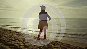 Happy kid playing alone on sea beach. Young girl have fun on morning ocean shore