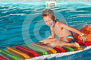 Happy kid playing in blue water of swimming pool.