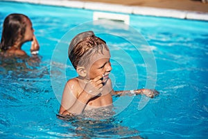 Happy kid playing in blue water of swimming pool.