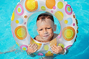 Happy kid playing in blue water of swimming pool. Little boy lea