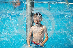 Happy kid playing in blue water of swimming pool on a tropical r