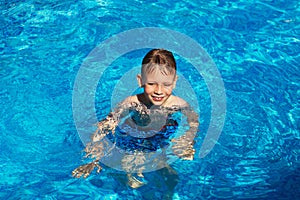 Happy kid playing in blue water of swimming pool on a tropical r