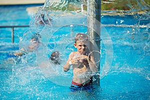 Happy kid playing in blue water of swimming pool on a tropical r