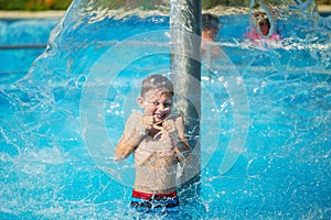 Happy kid playing in blue water of swimming pool on a tropical r