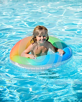 Happy kid playing with colorful swim ring in swimming pool. Child water toys. Children play in tropical resort. Family