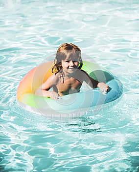 Happy kid playing with colorful swim ring in swimming pool. Child water toys. Children play in tropical resort. Family