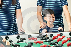 Happy kid playing foosball table with family.