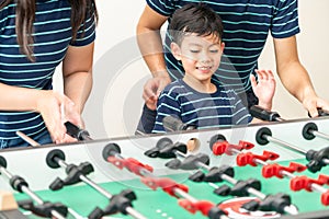 Happy kid playing foosball table with family.