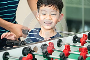 Happy kid playing foosball table with family.