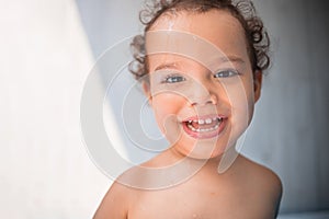 Happy kid playing in an inflatable pool in the backyard. Curly toddler smiling and playing with water