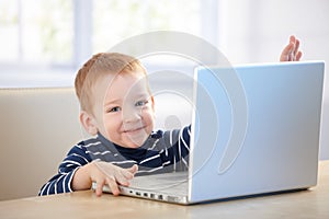 Happy kid playing with laptop at home