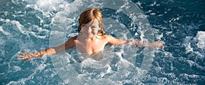 Happy kid playing in outdoor swimming pool on hot summer day. Kids learn to swim. Child in water. Children play in