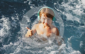 Happy kid playing in outdoor swimming pool on hot summer day. Kids learn to swim. Child in water. Children play in