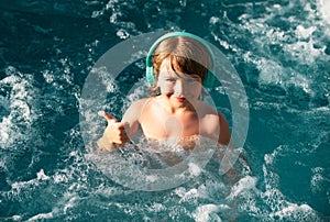 Happy kid playing in outdoor swimming pool on hot summer day. Kids learn to swim. Child in water. Children play in