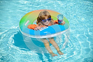 Happy kid playing with swim float ring in swimming pool. Summer vacation. Healthy child lifestyle.