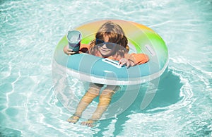 Happy kid playing with swim float ring in swimming pool. Summer vacation. Healthy child lifestyle.