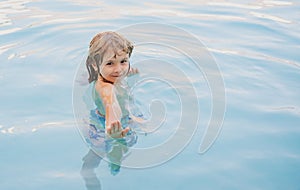 Happy kid playing in swimming pool. Child water games. Family vacation and summer activity.