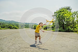 Happy kid playing with toy airplane against old runway background. Traveling with kids concept