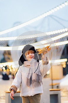 Happy kid playing with vintage wooden airplane outdoors. Portrait of children against the lights and sky.