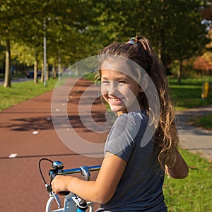 Happy kid rides a bike on a bike path.