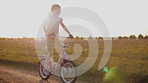 Happy kid riding bicycle in field at sunset, having fun outdoors