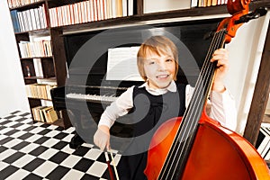 Happy kid in school dress playing on the cello