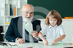 Happy kid in school. Teacher with pupil with airplanes. Education, teachering, elementary school.