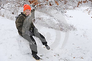 Happy Kid Sitting on Giant Snow Boulder Outside on a Winter Day