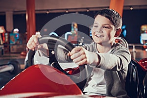 Happy kid sittng in toy car in amusement center