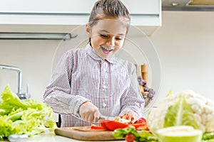 happy kid slicing pepper on chopping board
