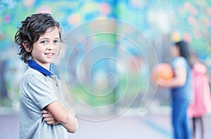 Happy kid smiling in schoolyard with other chilldren playing on