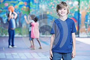 Happy kid smiling in schoolyard with other chilldren playing on