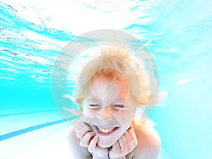 Happy Kid Smiling Under Water as he Swims in a Pool