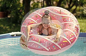 Happy kid swim in donut pool float in swimming pool on sunny summer day, floatation