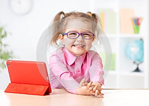 Happy kid with tablet PC in glasses as early