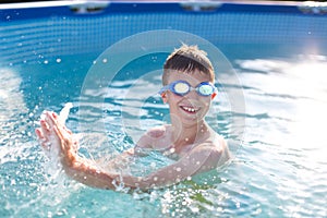Happy kid with teeth smile splasing in swimming pool
