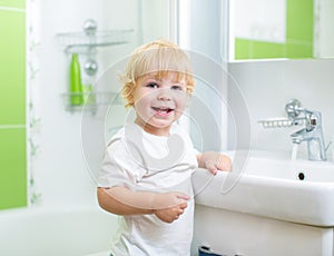 Happy kid washing hands in bathroom