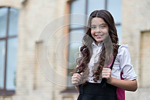 Happy kid wear long wavy hair with back to school look in schoolyard, salon, copy space