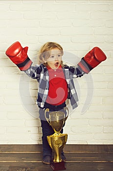 Happy kid winner in boxing glove winning golden champion cup