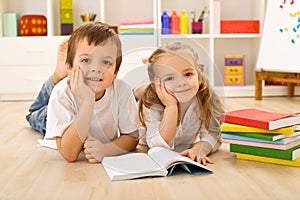 Happy kids with books laying on the floor