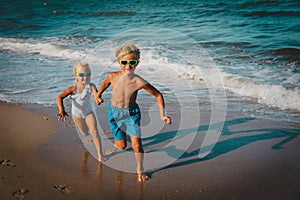 Happy kids- boy and girl -running on beach