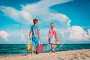 Happy kids- boy and girl with toys come to sand beach