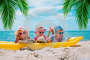 Happy kids- boy and girls read books on beach, family vacation