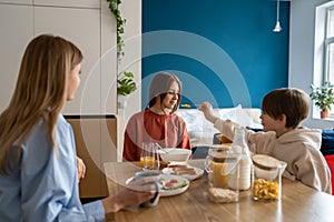 Happy kids brother and sister have fun while eating cereals in morning at home