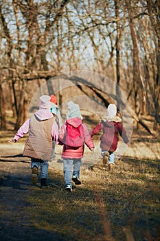 Happy kids, classmates, boys and girls, with backpacks feet walking in forest on bright day. Outdoor activities for